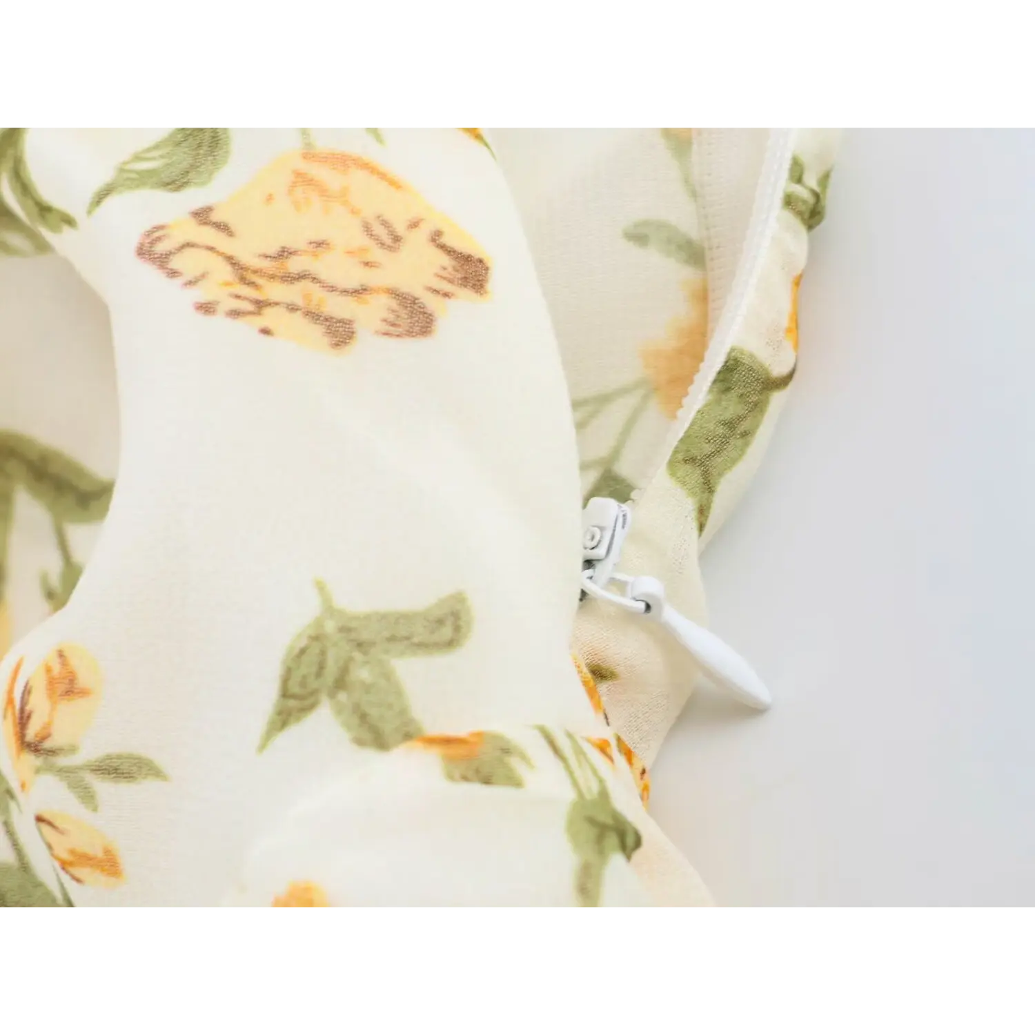 Close-up of white invisible side zipper on yellow floral chiffon dress