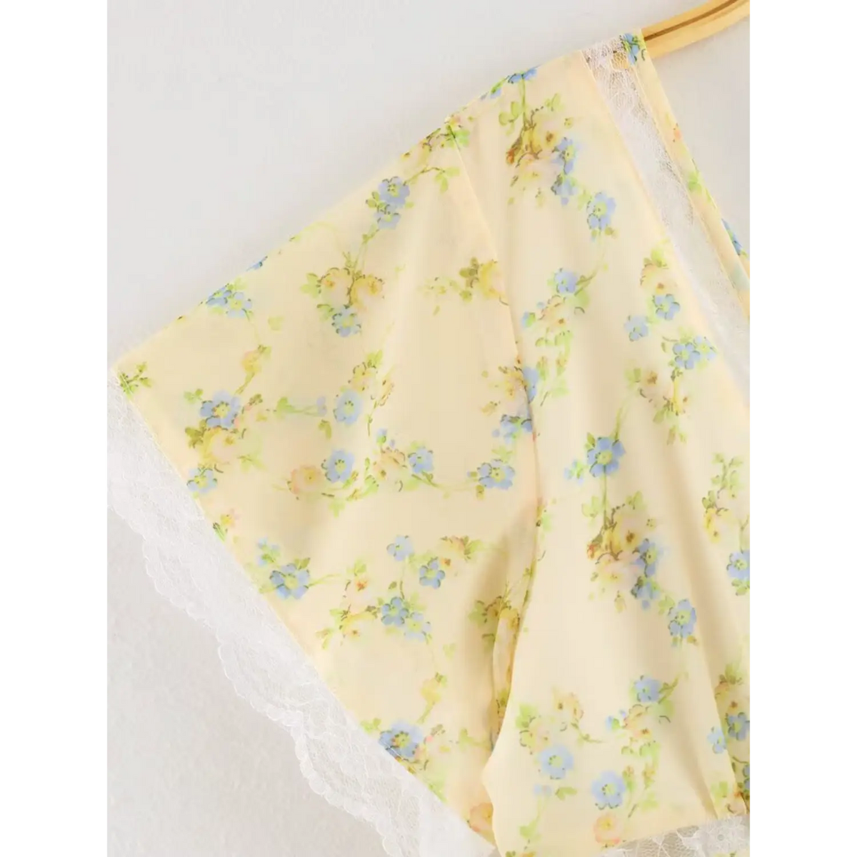 Partial shot of flutter short sleeve, yellow floral chiffon with white lace scalloped edge