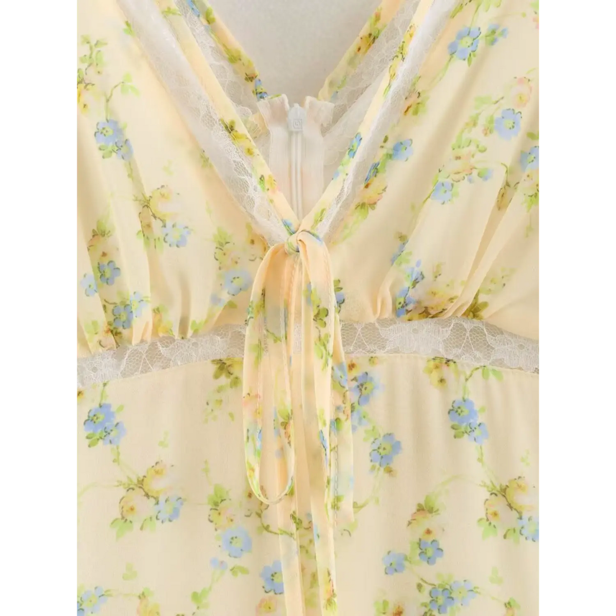 Close up of front tie knot and invisible zipper, white lace trim on yellow floral maxi dress