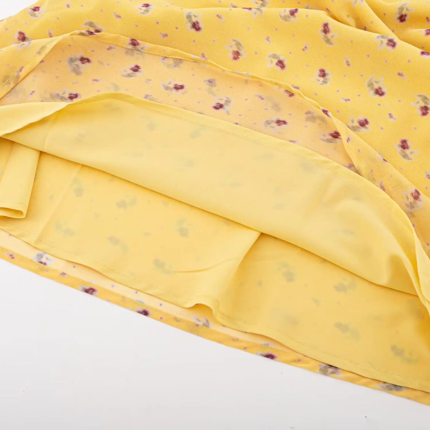 Flat lay overhead shot, hem detail showing outer chiffon fabric and solid yellow lining