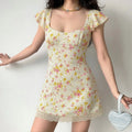 Model wearing a pale yellow floral mini dress with a square neckline, ruffled sleeves, and lace hem.