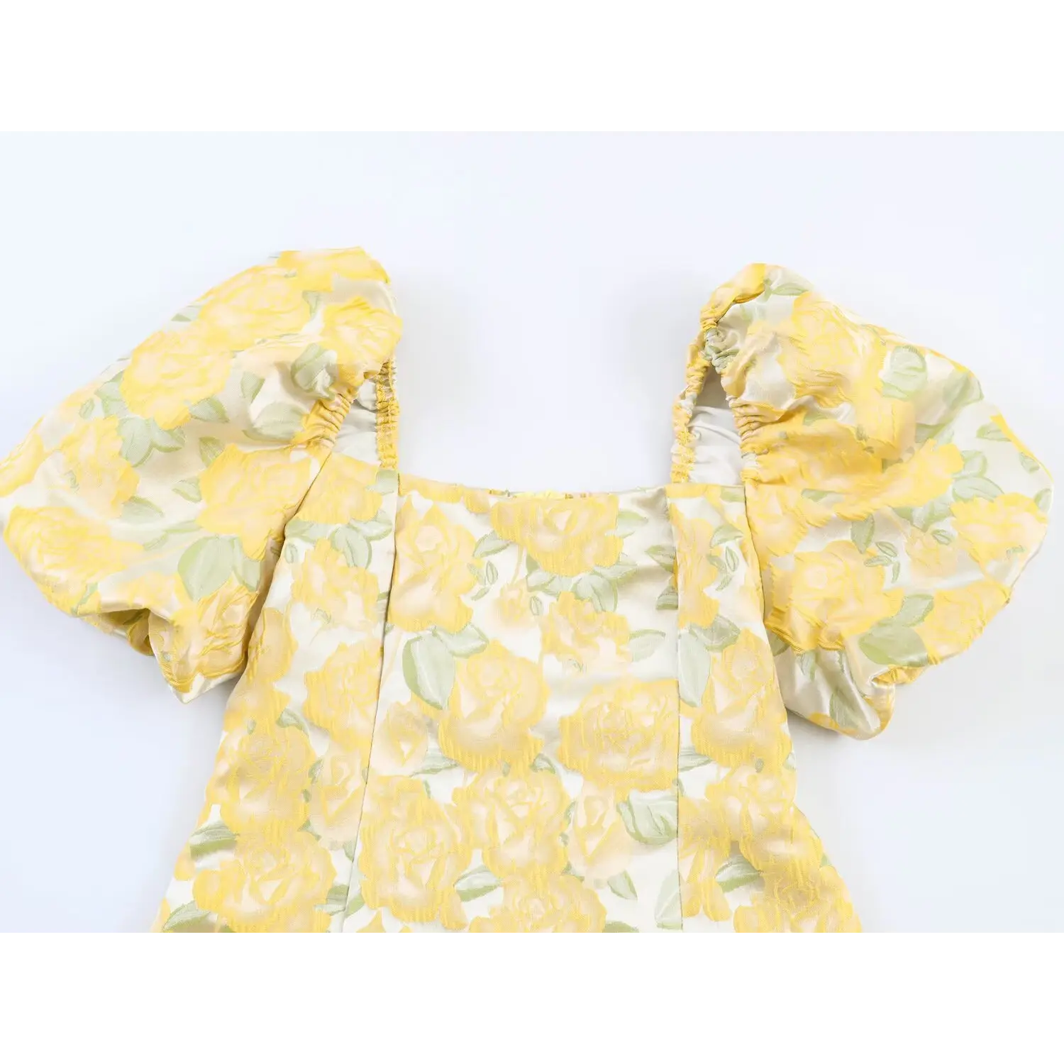 Close-up shot of square neckline and puff sleeves on yellow rose embossed floral mini dress