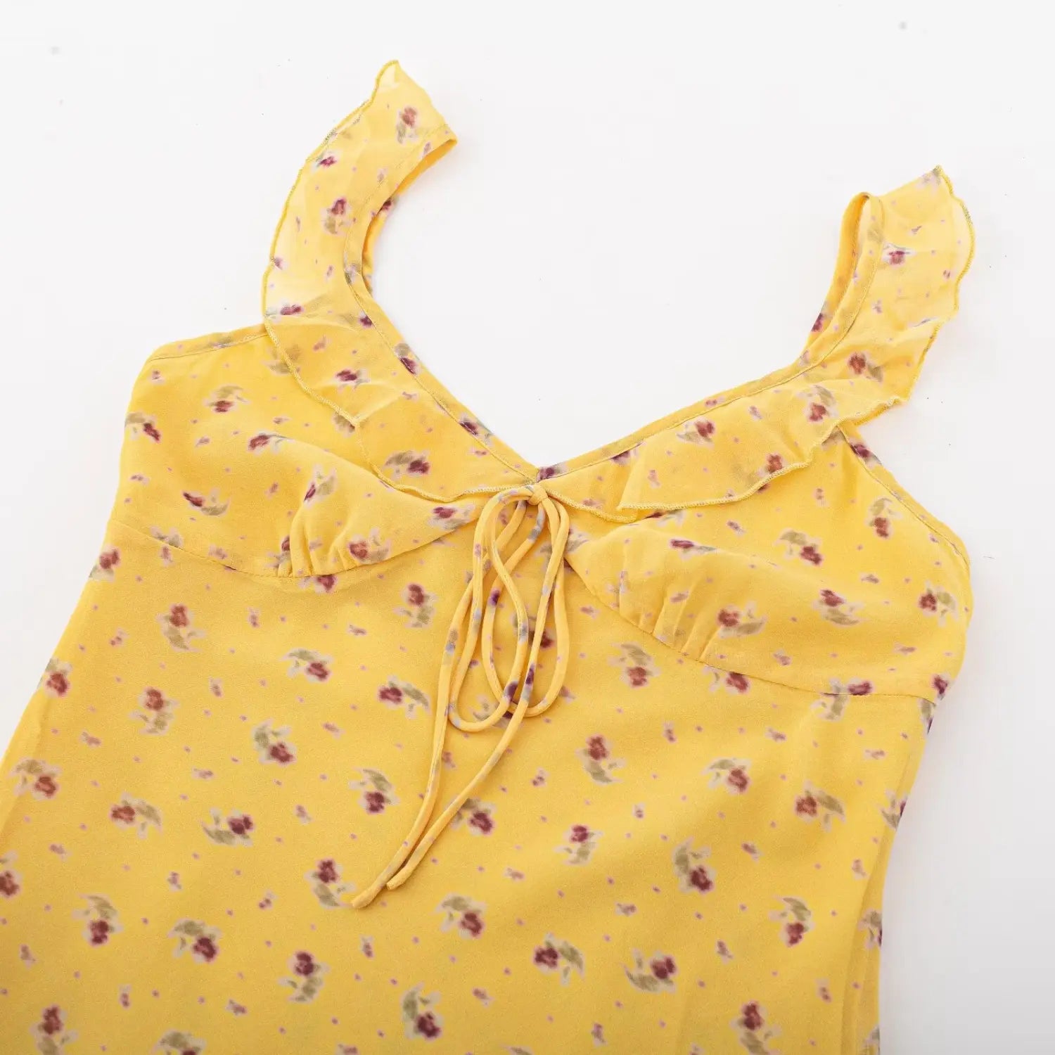 Flat lay shot, yellow floral v-neck mini dress showing ruffle shoulder and front tie design