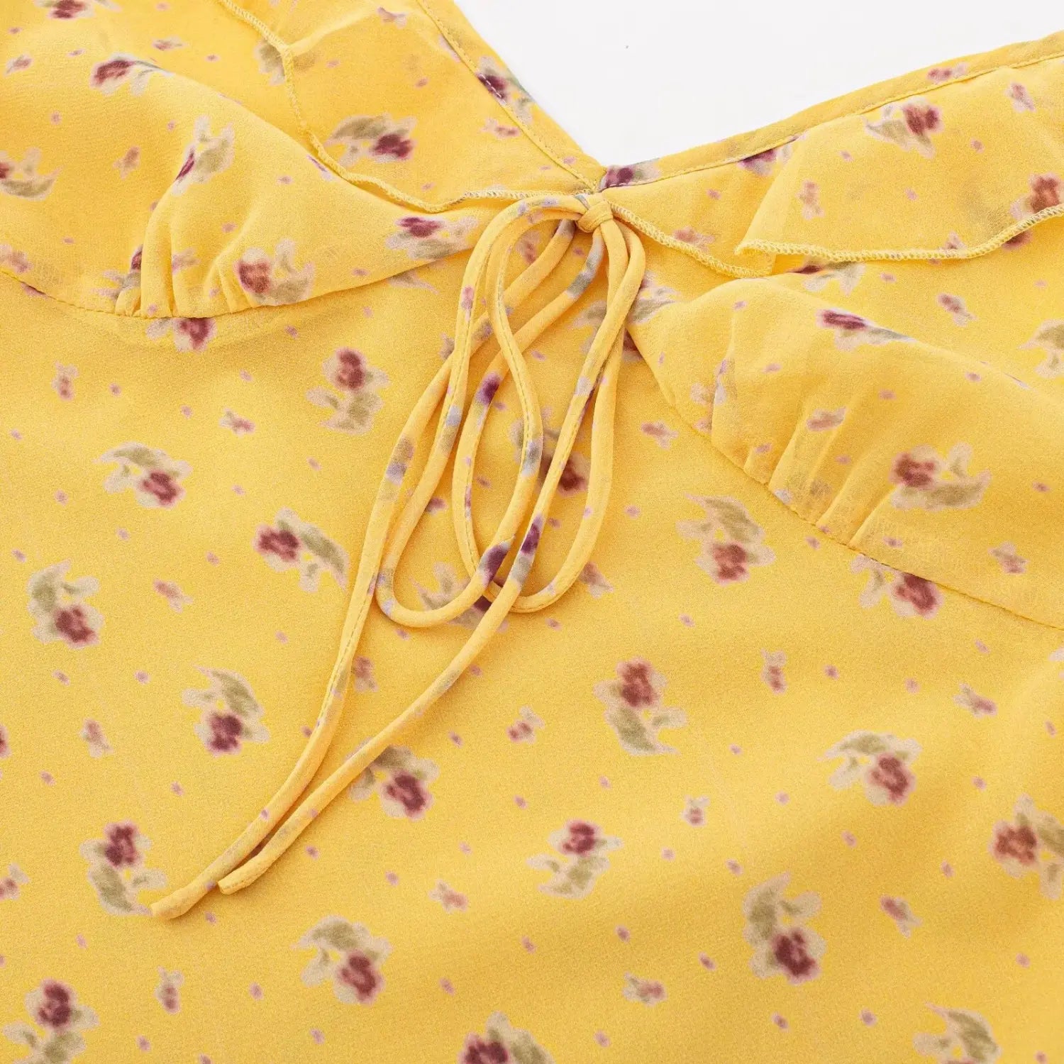 Macro closeup of front tie knot detail on yellow floral print chiffon mini dress