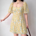 Model wearing yellow embossed rose print mini dress with square neck and bubble short sleeves