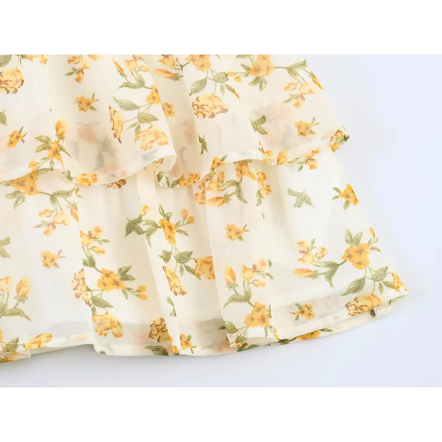 Detail view of multi-layer tiered ruffle skirt hem with yellow floral chiffon