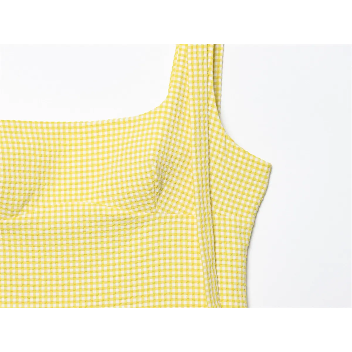 Neckline detail of yellow gingham dress, showing the square neckline and textured fabric