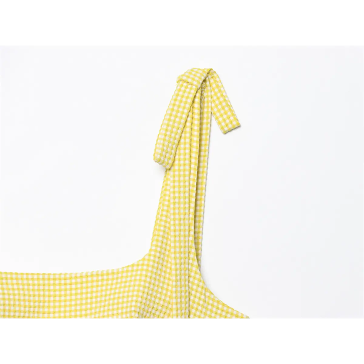  Close-up of the tied bow strap on the yellow gingham dress, showing the knot and fabric texture
