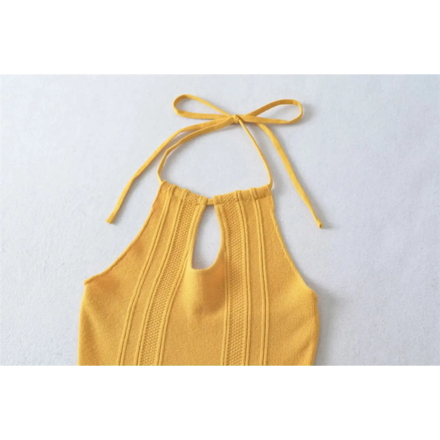 Mustard yellow halter knit mini dress neck flat lay, matching fabric tie keyhole bust vertical rib knit white background photo
