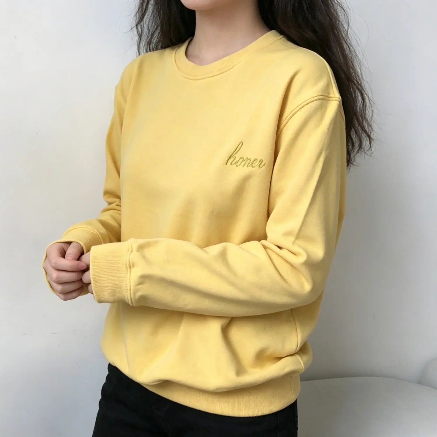 Model side view wearing soft yellow crewneck sweatshirt with honey cursive embroidery on chest