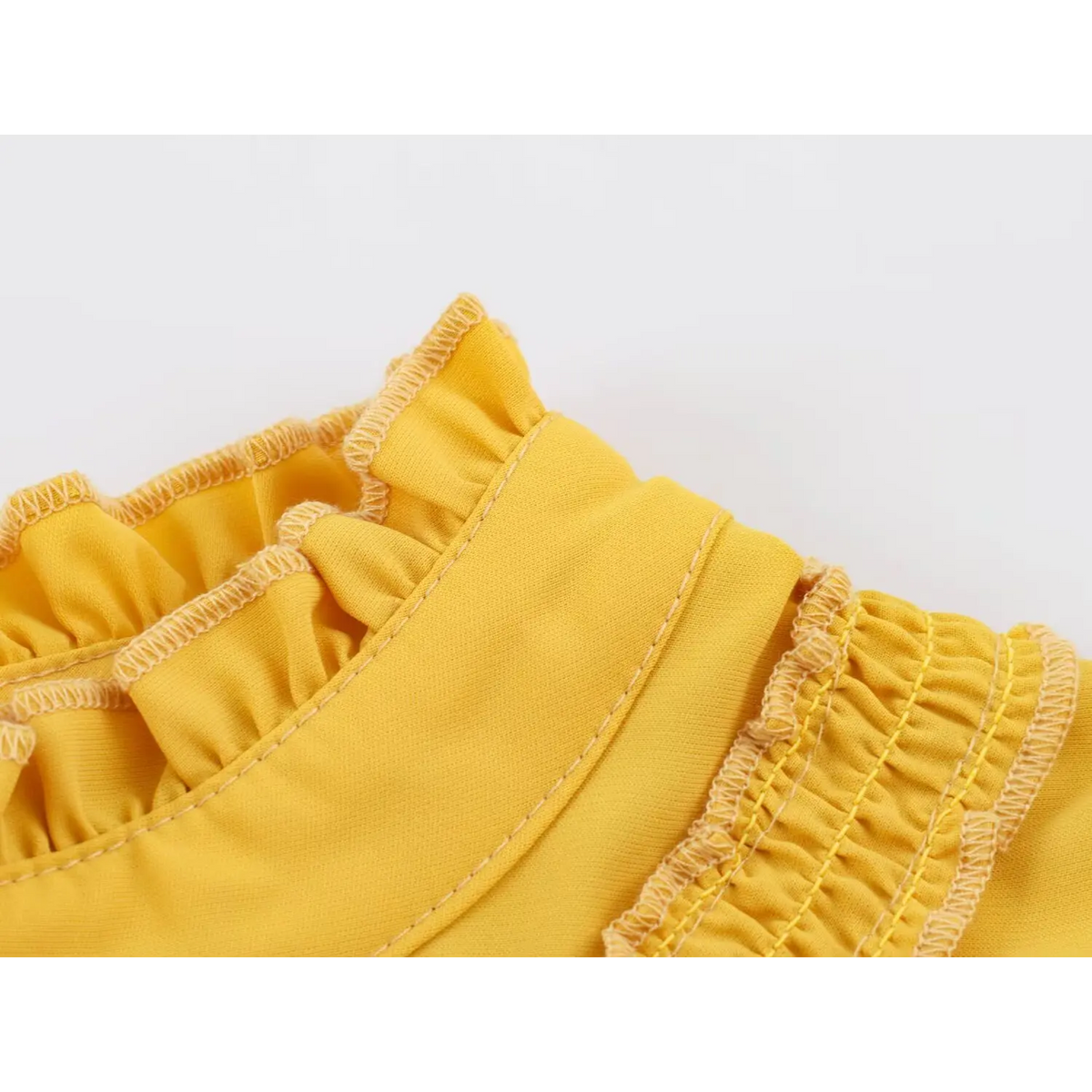 Close-up of ruffled trim with neat stitching on bright yellow fabric