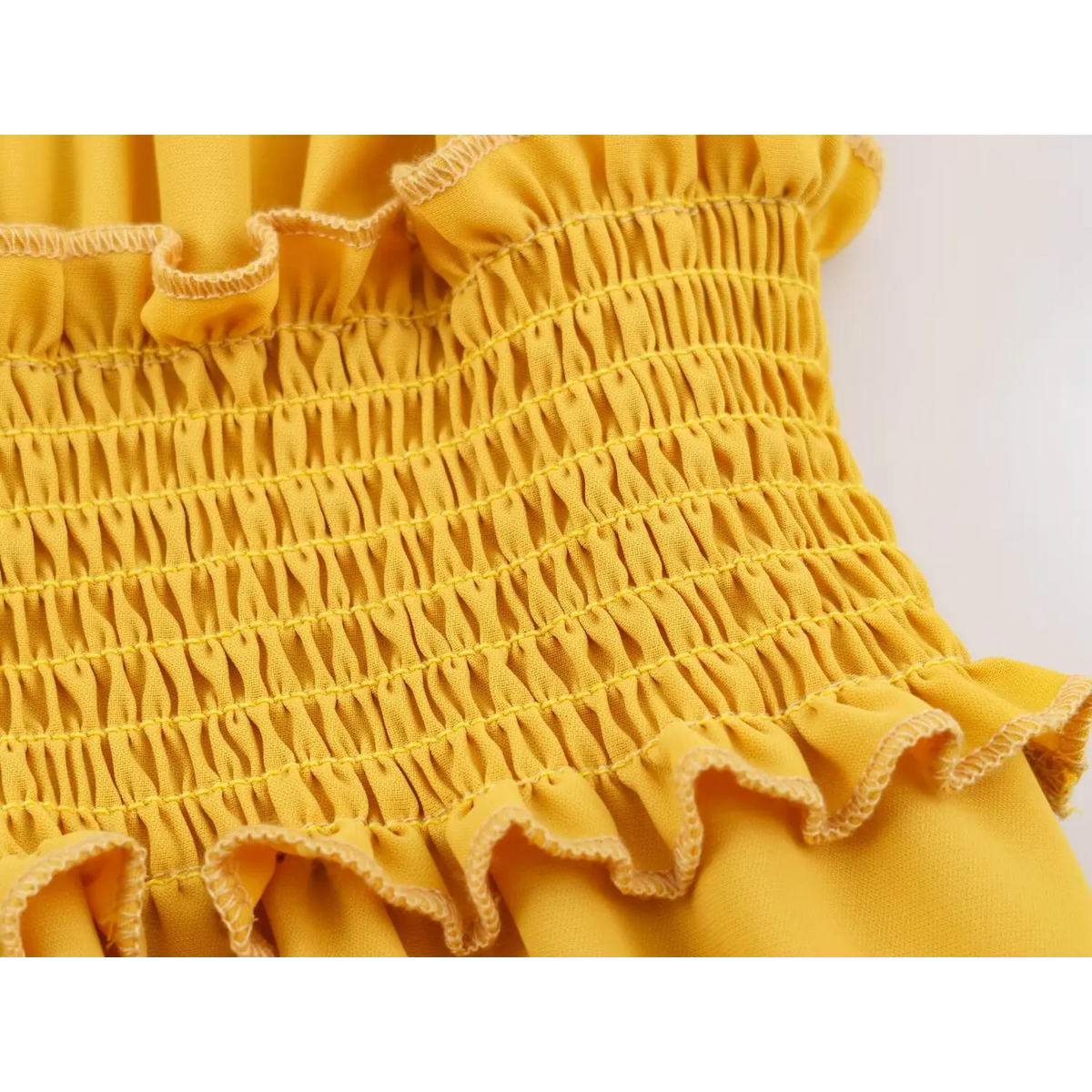 Close-up of parallel shirred rows and ruffle edge on yellow dress fabric