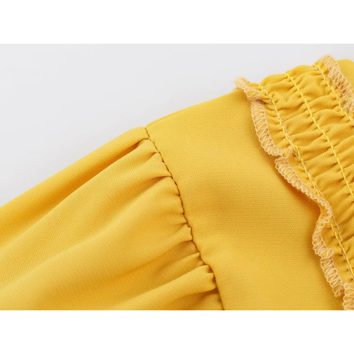 Close-up of elastic shirring and cream lockstitch seams on yellow fabric