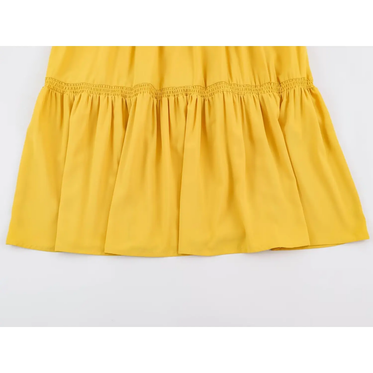 Close-up of shirred waistband and softly gathered tiered skirt on yellow dress