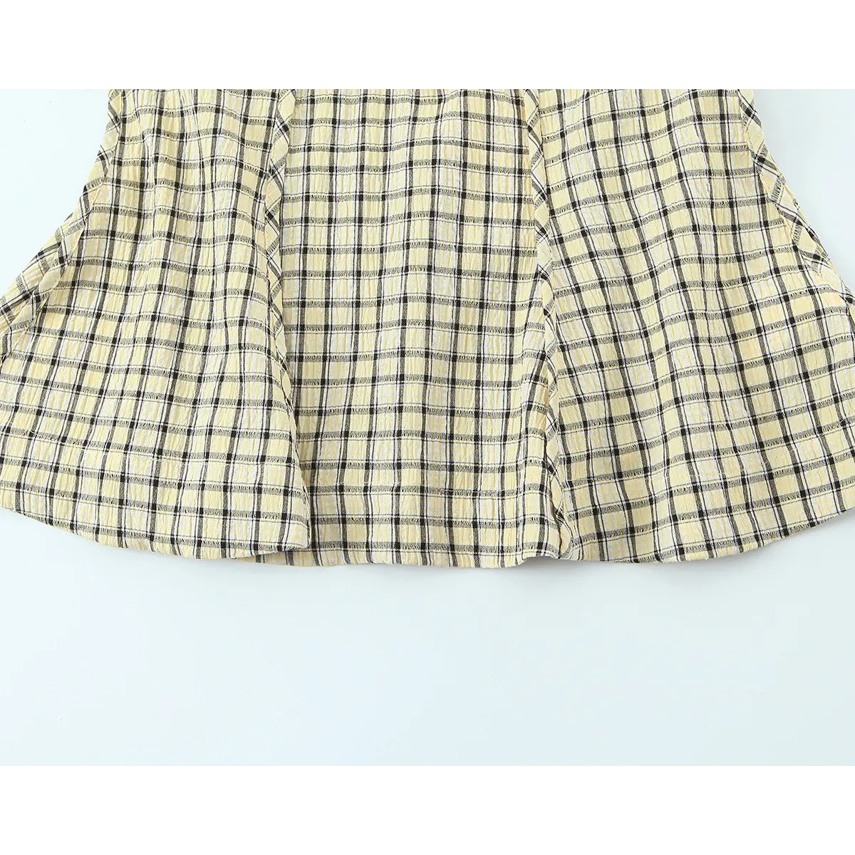 View of the flared camisole hem, showcasing the A-line silhouette and textured plaid pattern