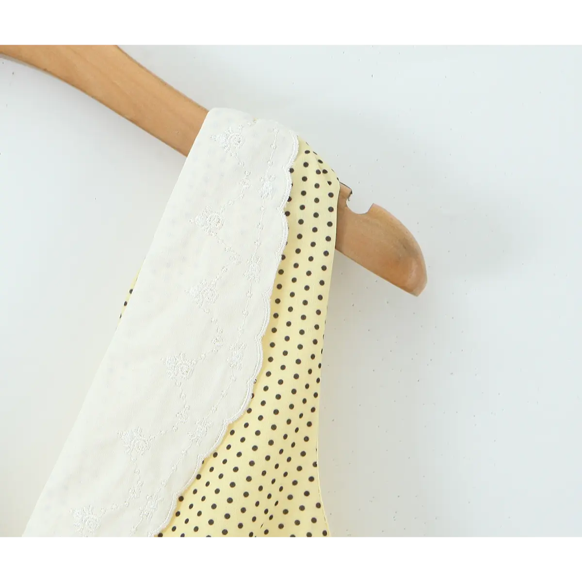 Closeup of floral embroidered lace V collar on yellow dot sundress