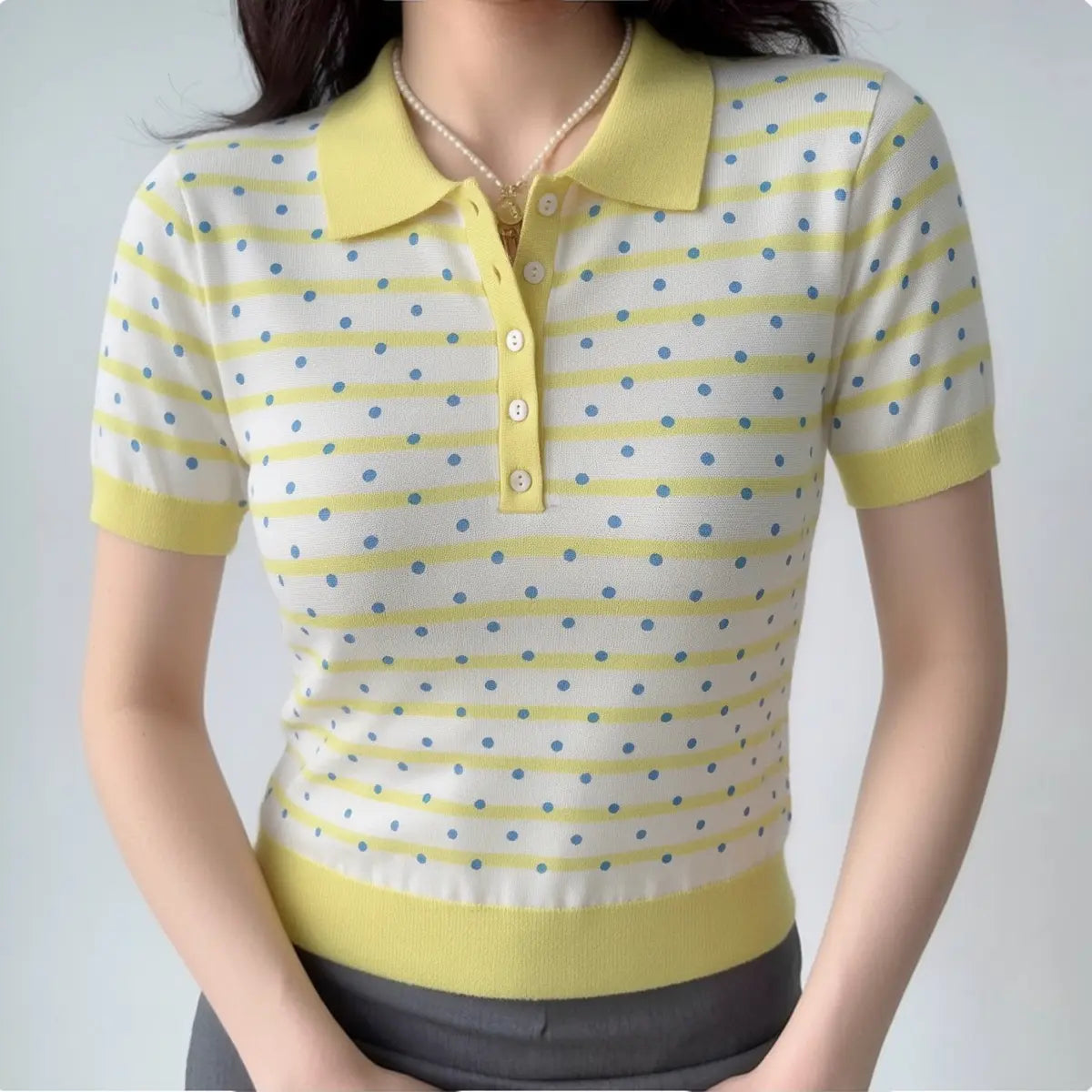 Model wearing a yellow and white polka dot knit polo shirt, showcasing the fitted silhouette, ribbed collar, and casual preppy style.