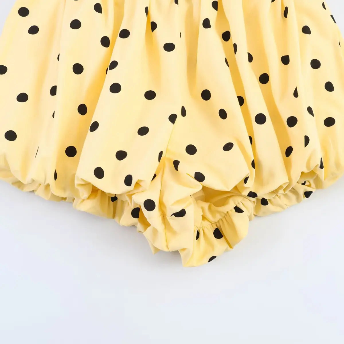 Close-up of the gathered leg opening and puffed silhouette on the yellow polka dot shorts