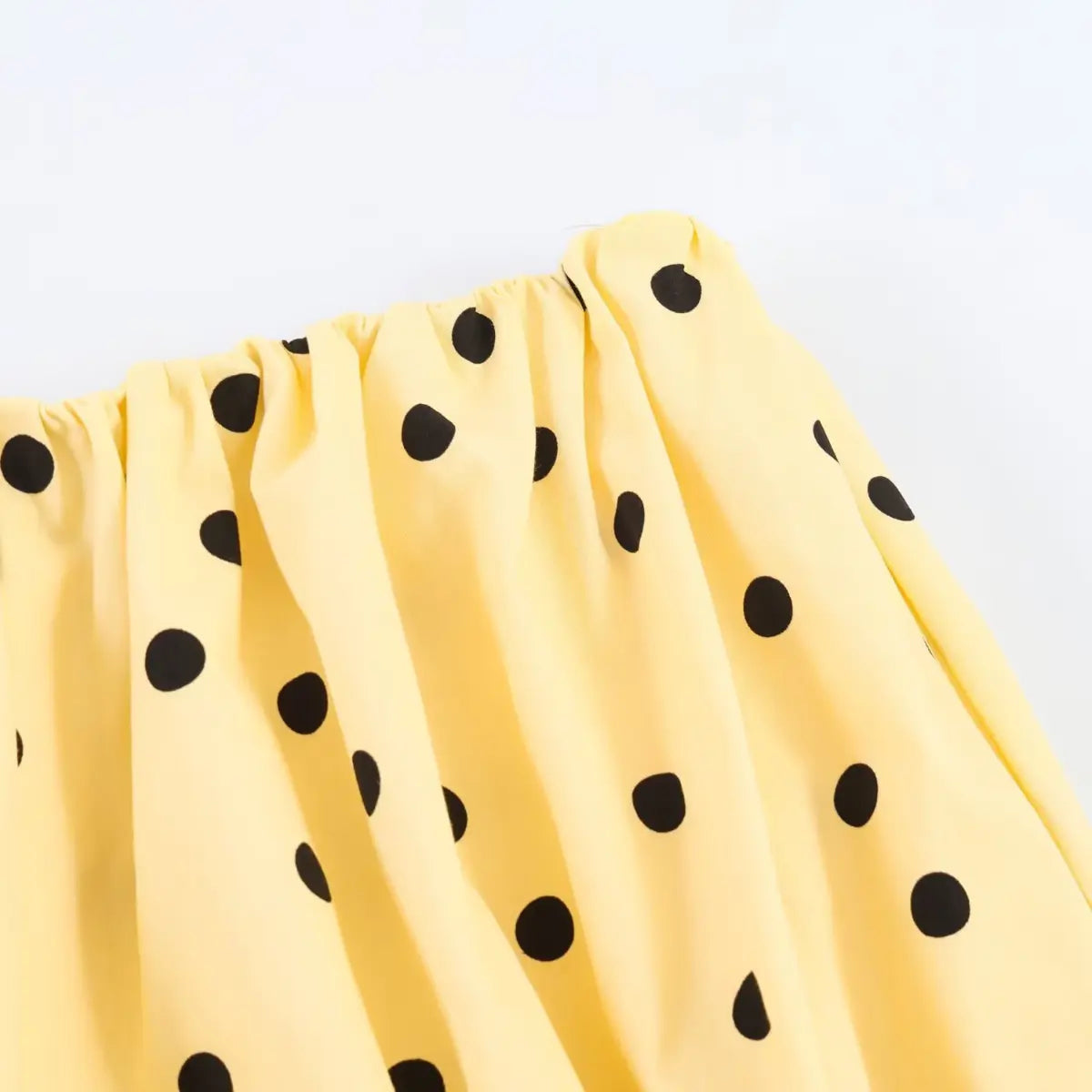Close-up of the elastic waistband and fabric texture on the yellow polka dot shorts