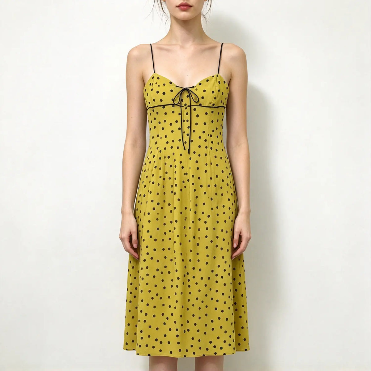 Model wearing yellow polka dot spaghetti strap maxi dress with front tie detail, sweetheart neckline, flowy skirt, white background