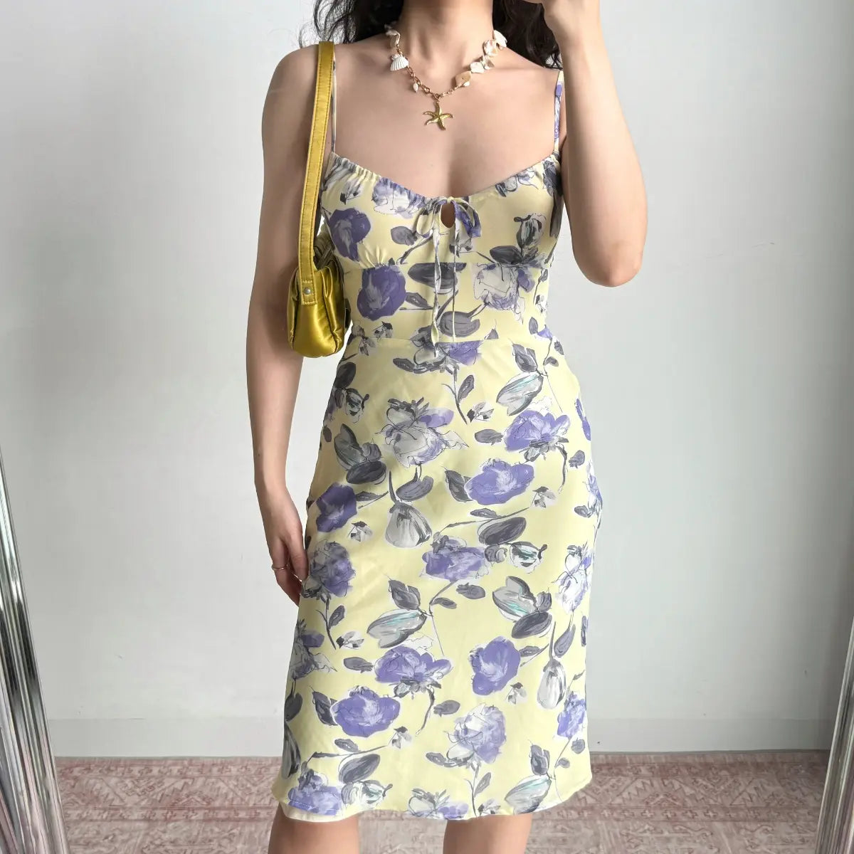 Front view of a yellow floral midi dress with purple flowers, keyhole neckline, and spaghetti straps.