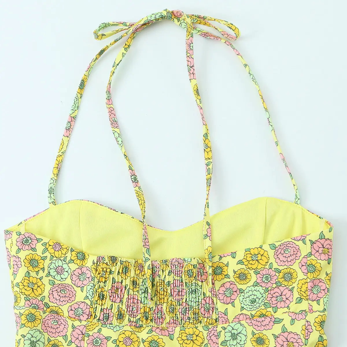 Back view of the yellow floral halter top, showing the elasticated smocked back panel, tie straps, and matching floral print lining