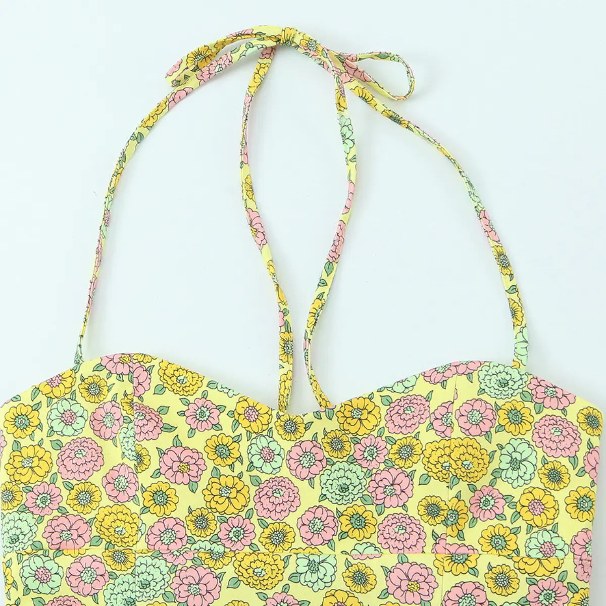 Front view of the yellow floral halter top, featuring a sweetheart neckline, tie straps, and a retro pink, yellow, and green floral print