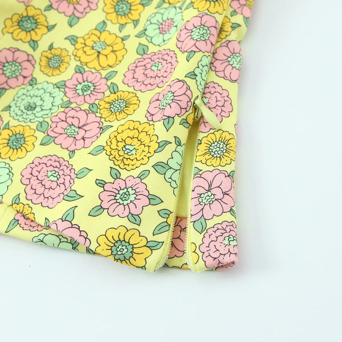 Close-up of the side zipper on the yellow retro floral halter top, showing the matching yellow zipper pull and pastel floral print