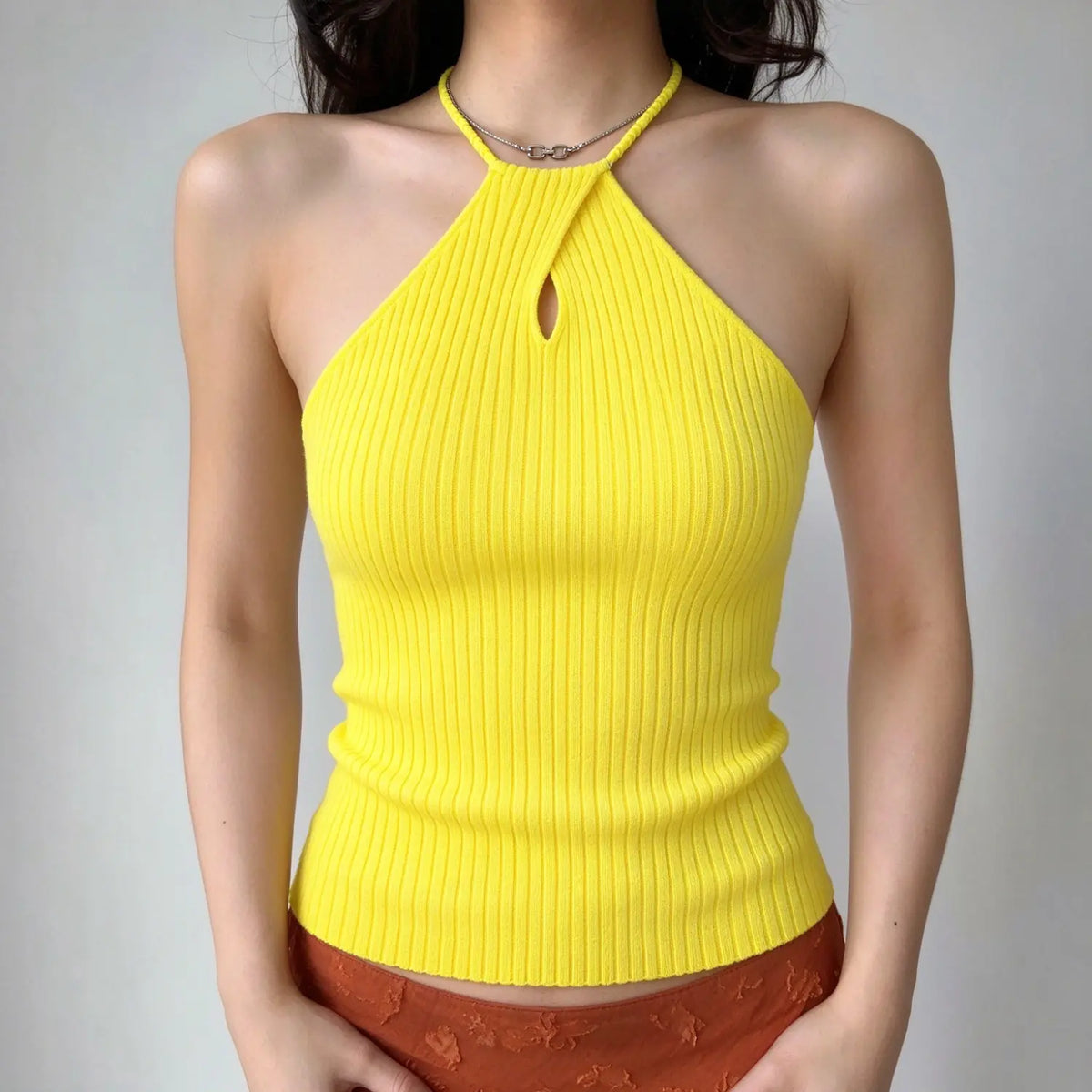Model wearing bright yellow ribbed knit halter top, small keyhole cutout at front, slim cropped fit, front view