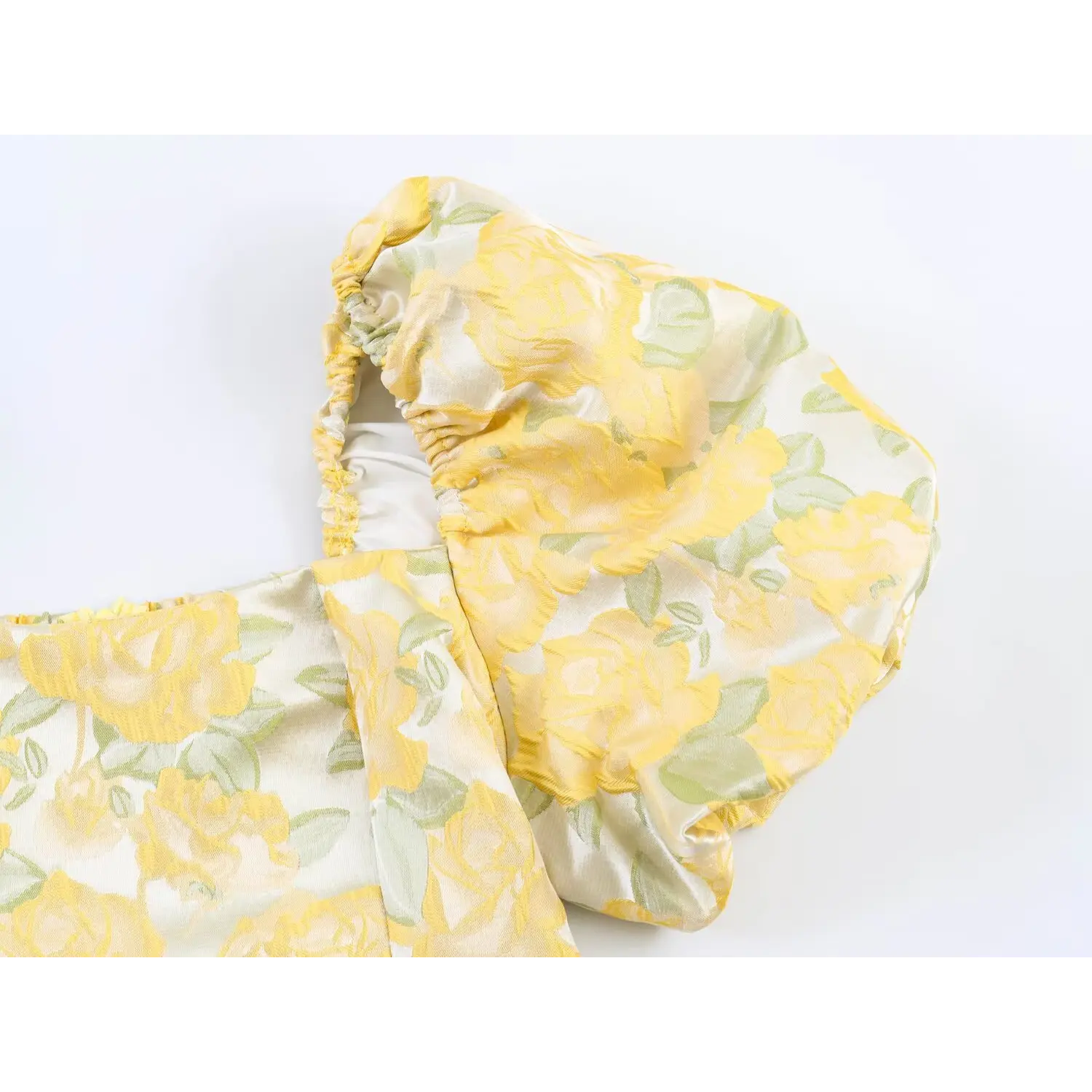 Detail close-up of elasticated puff sleeve with yellow floral embossed fabric