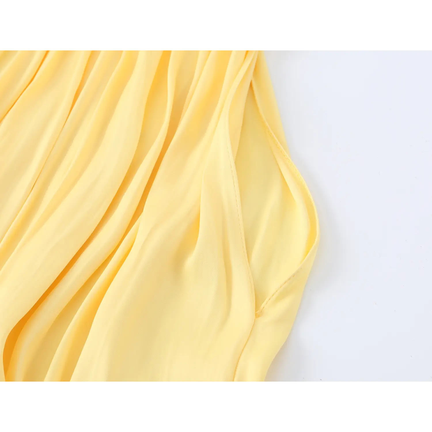 Close-up of fabric drape and side seam, smooth matte yellow lightweight fabric, fine internal stitching, natural soft wrinkle texture