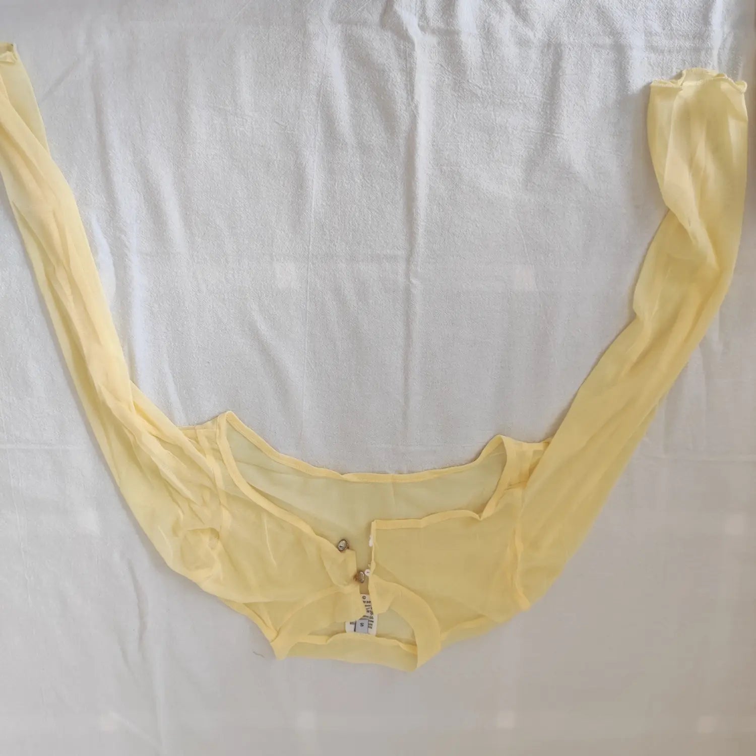 Flat lay pale yellow sheer mesh cutout long sleeve shrug cover up
