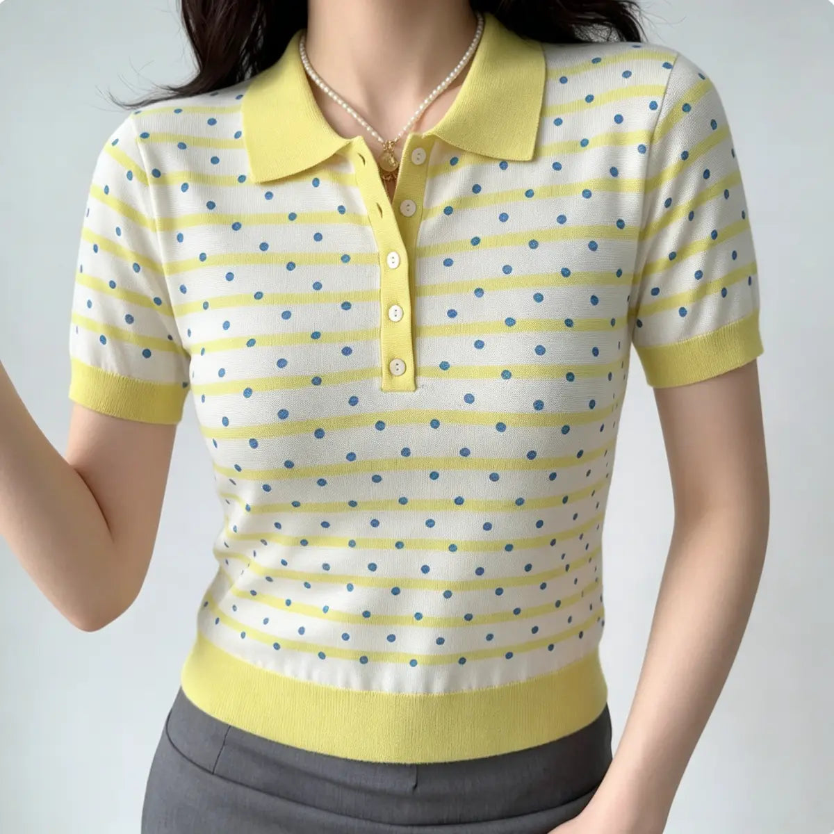  Front view of a yellow and white polka dot knit polo shirt, highlighting the ribbed collar, button placket, and short sleeves.