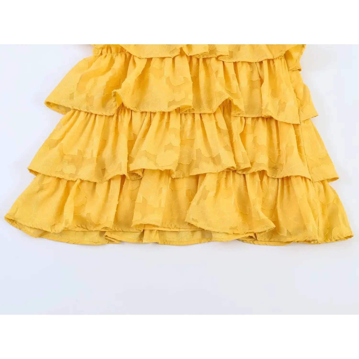 Close-up shot of the tiered ruffle skirt hem of the yellow floral dress