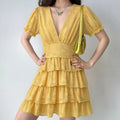 Lifestyle shot of a woman wearing the yellow textured floral dress, with hands on her hips and a yellow handbag