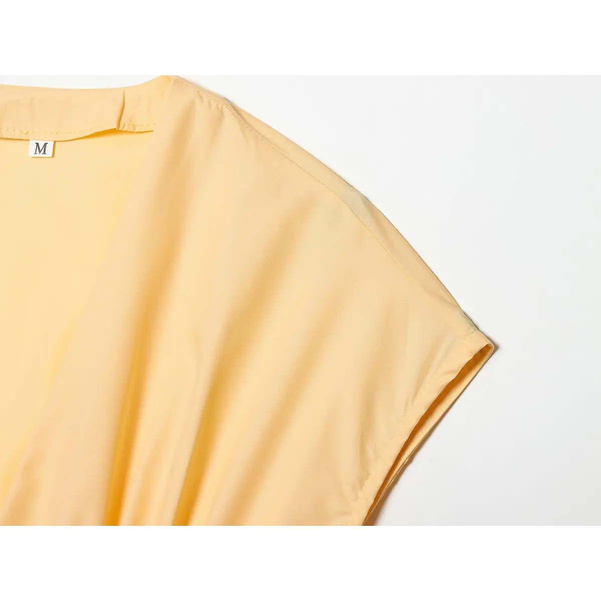 Close-up of the dress's V-neckline, cap sleeve, and inner size label.
