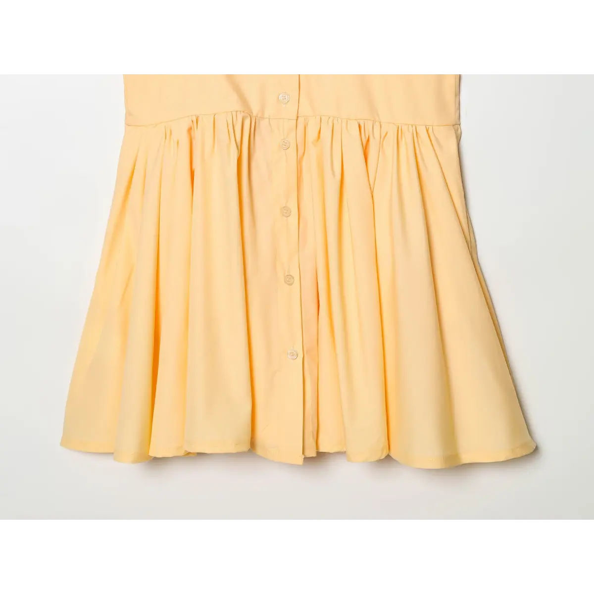 Close-up of the dress's skirt hem, showing the finished edge and buttons.
