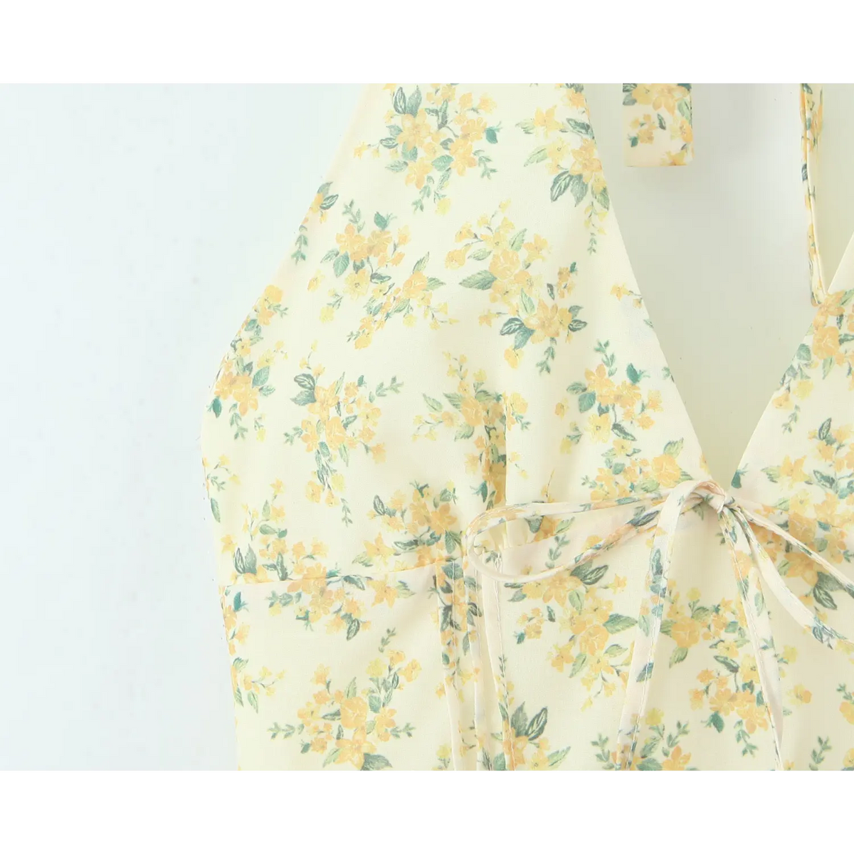 Fabric close‑up showing front tie bow and yellow green floral print of halter mini dress