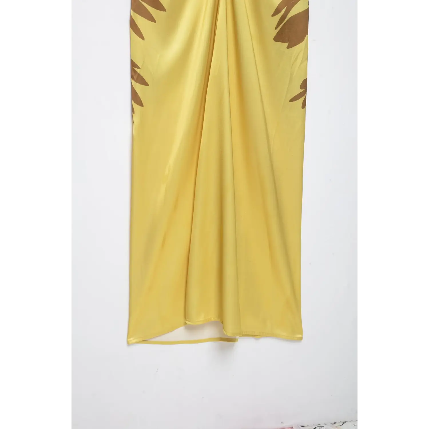 Close‑up of back skirt fabric for yellow halter maxi dress, displaying satin drape and side floral print pattern
