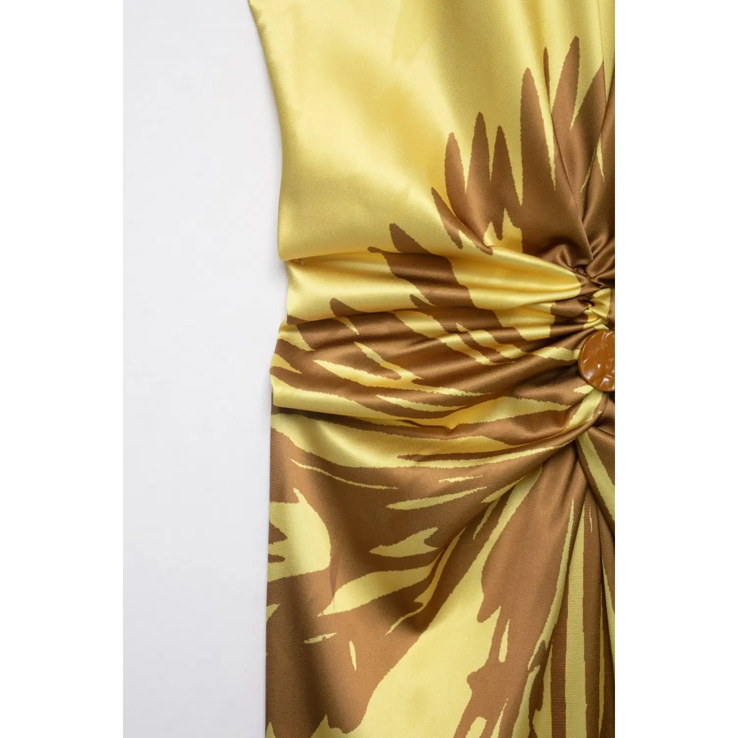 Side partial close‑up of yellow satin maxi dress, waist twist knot construction and large brown abstract floral print