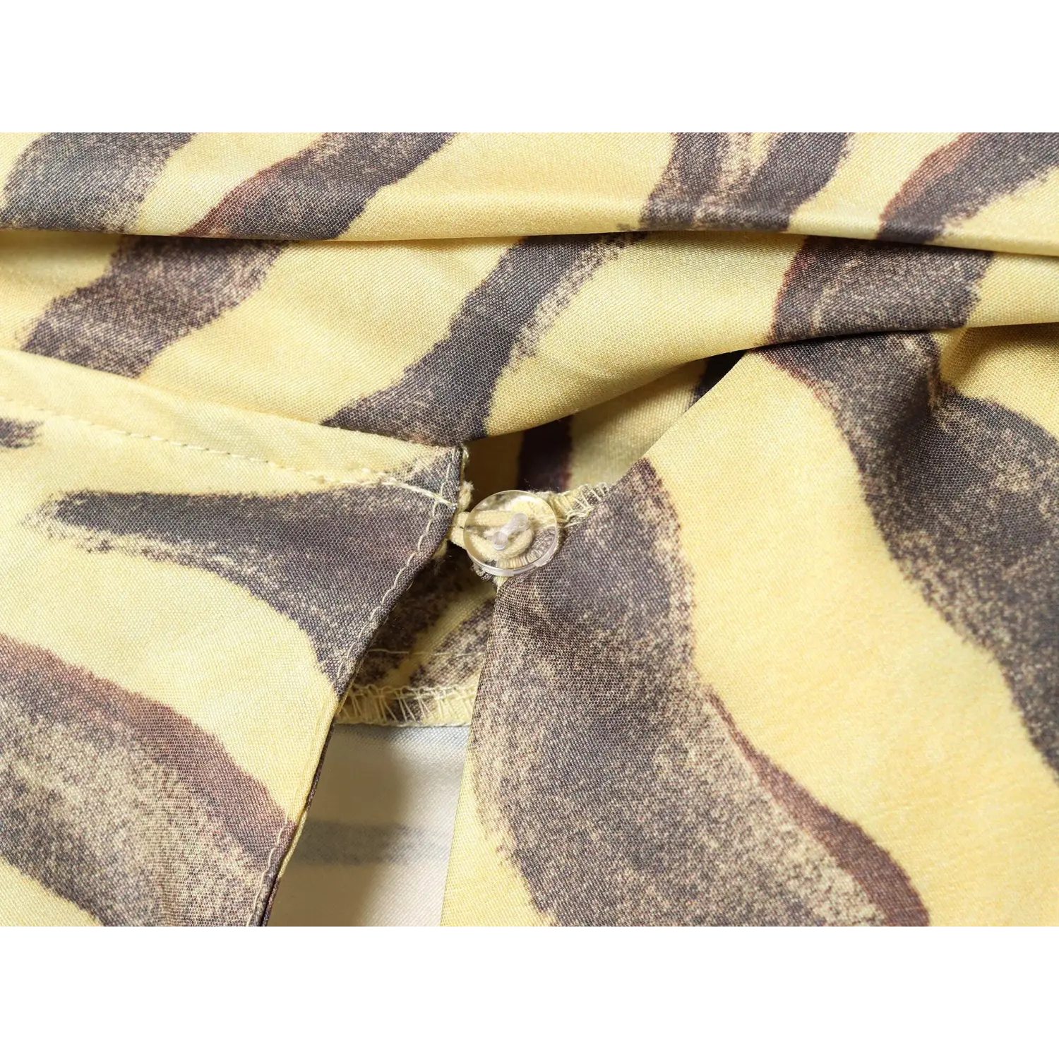 Extreme close‑up of transparent back button closure for keyhole opening on zebra print satin dress