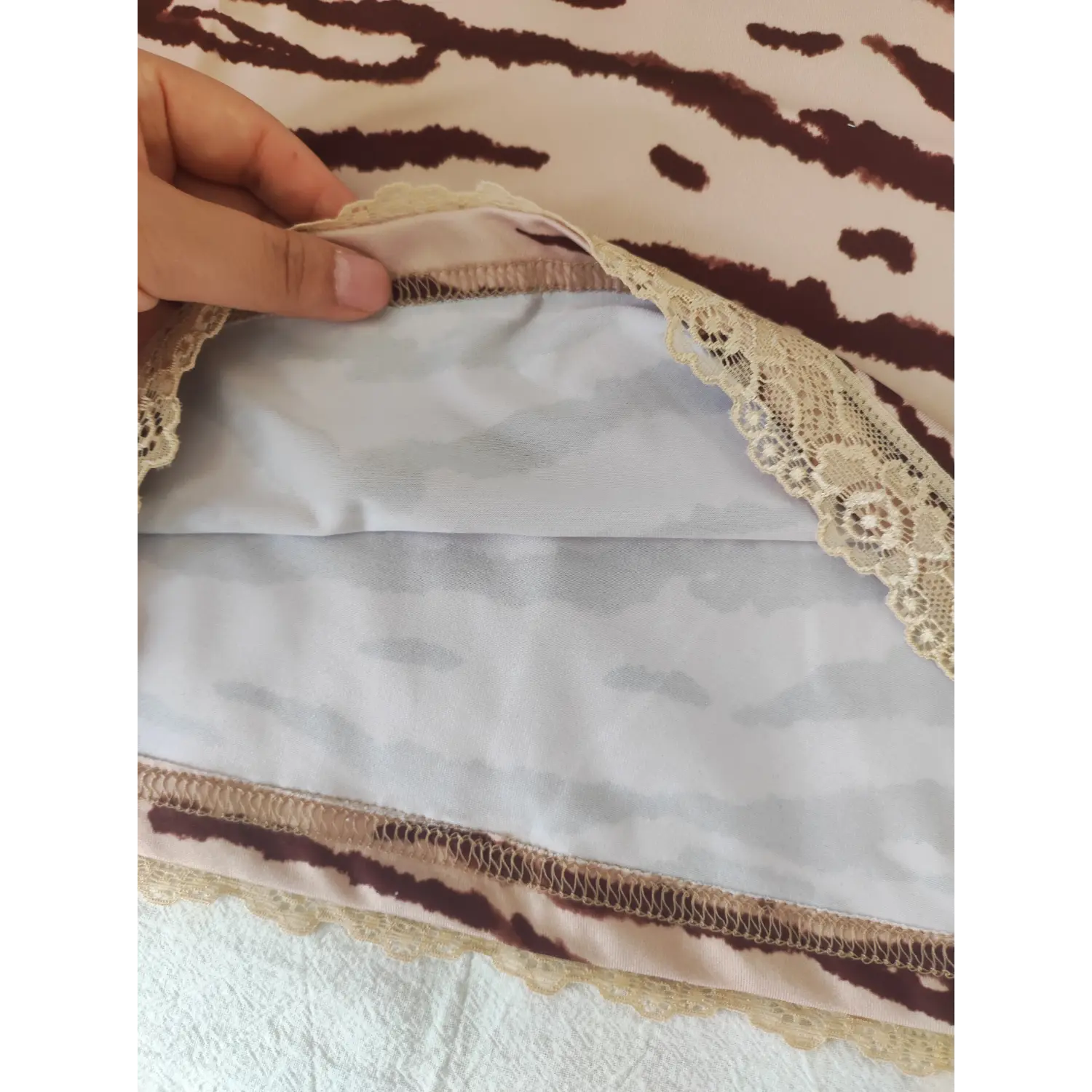 Hand shot showing inner lining and lace hem stitching on pink zebra cami dress
