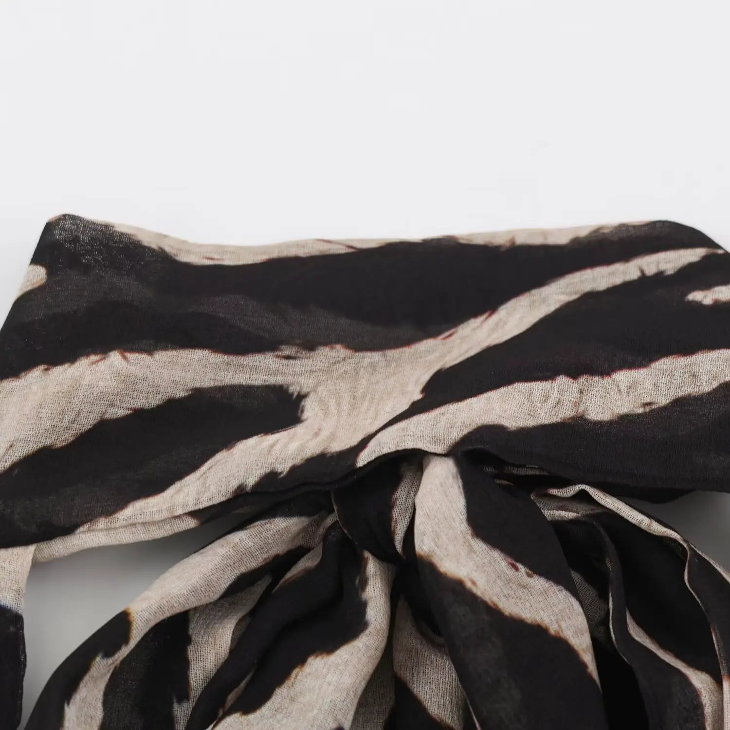 Macro close‑up of halter neck knot on zebra print maxi dress, chiffon fabric texture
