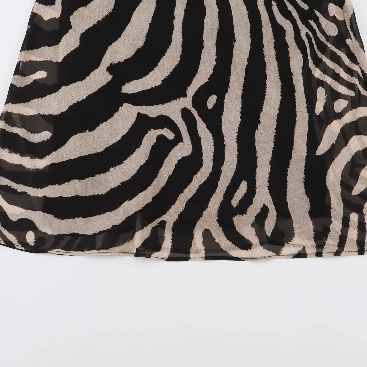 Flat close‑up of skirt hem on zebra print chiffon maxi dress, full skirt pattern display